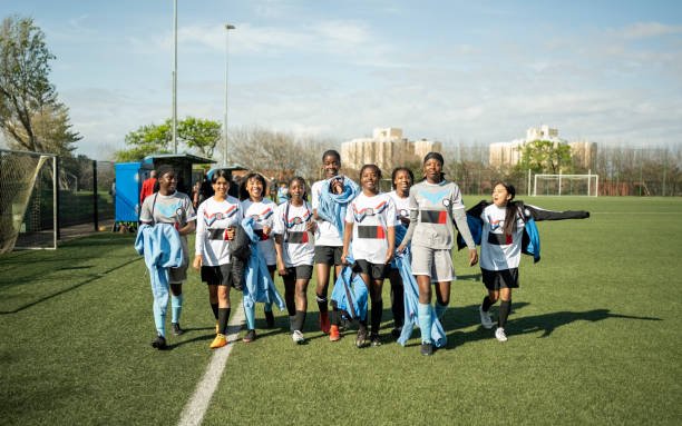 Full length portrait of a team of young female soccer players walking together after the practice session on sports field