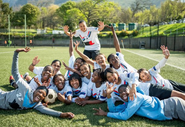 Team of young female soccer players cheering on field after their football game