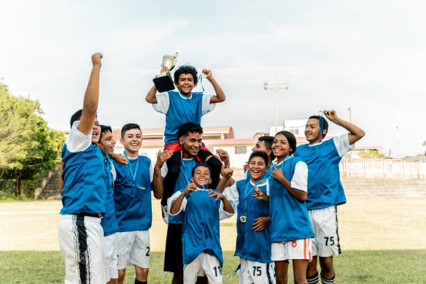 Soccer team celebrating with trophy and medal on a soccer field